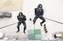 借助绳索,队员从高楼飞跃而下.